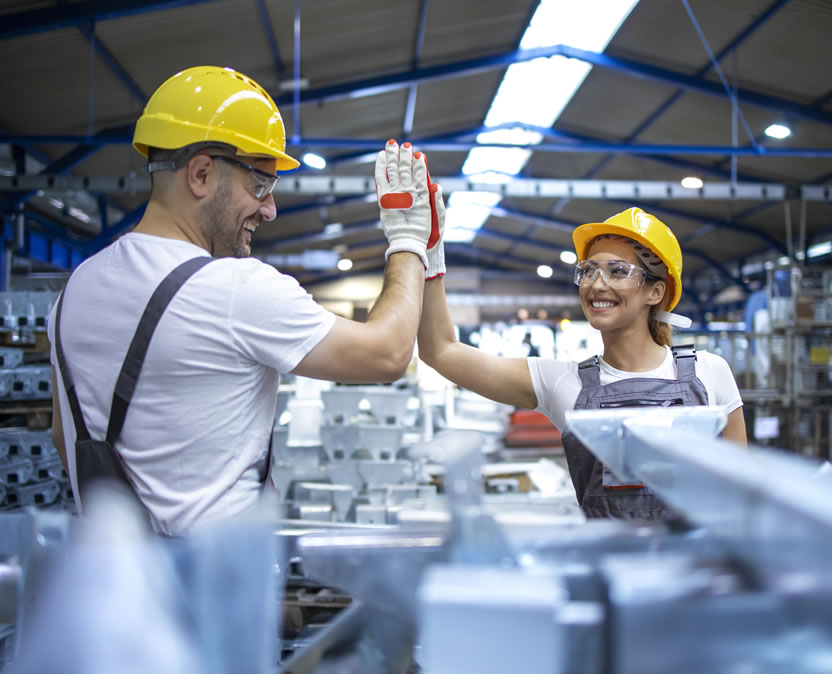 Dois funcionários da indústria apertam as mãos dentro da fábrica